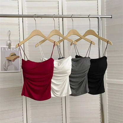 Four strap tops in red, white, gray, and black hanging on a rack against a neutral background. Corset taille cintrée élégant, sans manches avec pliage, coussinet poitrine, bretelles fines, top court solide, mode UK FTF Market.