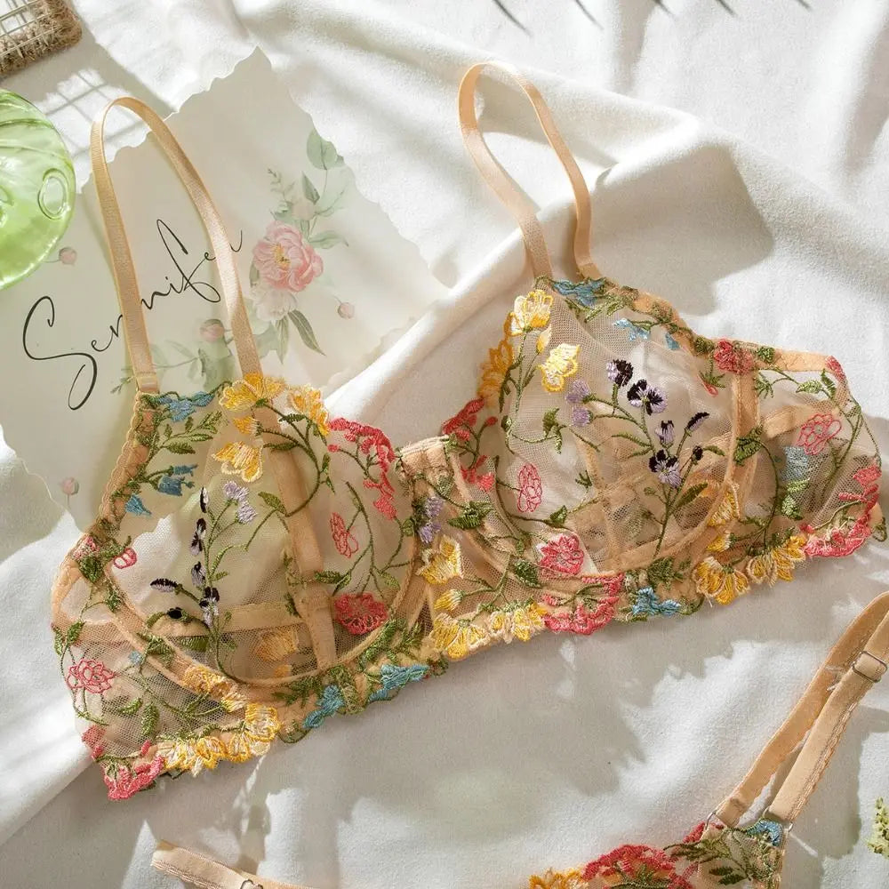 Floral embroidered bra and panties set on a white surface with a Scunci hair product in the background.