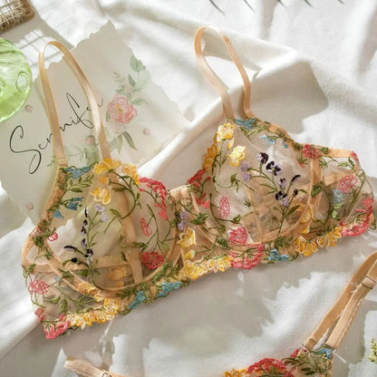 Floral embroidered bra and panties set on a white surface with a Scunci hair product in the background.