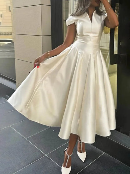Woman wearing a white dress standing on a tiled floor.