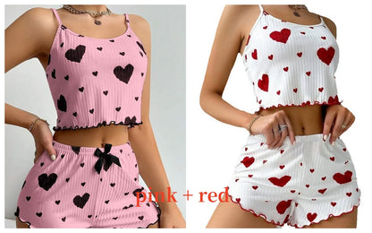 Two outfits with heart patterns, one pink and black, the other white and red, on a plain background. Soft women’s pajama set, 2 pieces white tank top and shorts, breathable fabric with love print, comfortable casual sleepwear, UK FTF Market.
