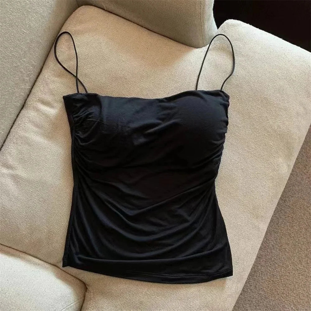 Black satin camisole on a beige sofa. Corset taille cintrée élégant, sans manches avec pliage, coussinet poitrine, bretelles fines, top court solide, mode UK FTF Market.