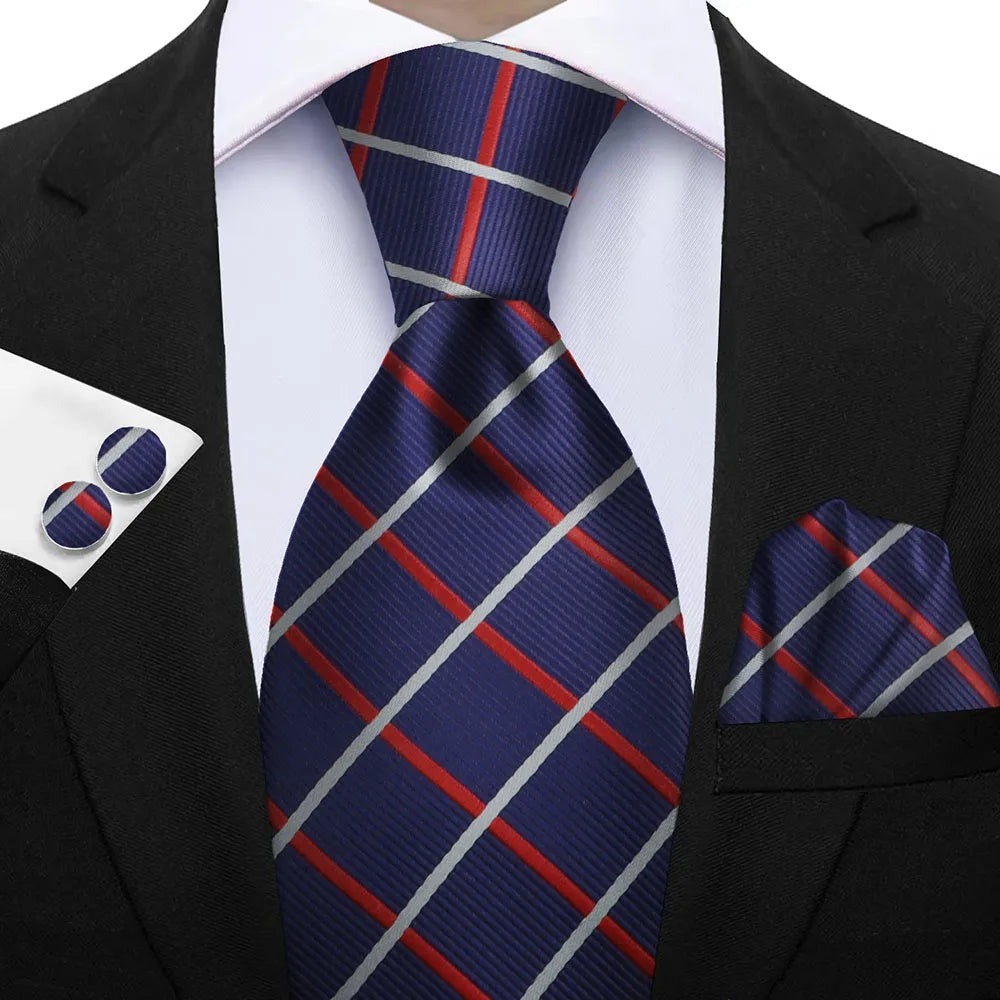 Navy blue tie with red and gray stripes paired with a matching pocket square and cufflinks on a suit. Elegant men’s 3-piece tie set: striped necktie, floral pocket square, matching cufflinks. Fashionable polyester accessories for formal occasions.