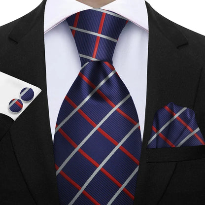 Navy blue tie with red and gray stripes paired with a matching pocket square and cufflinks on a suit. Elegant men’s 3-piece tie set: striped necktie, floral pocket square, matching cufflinks. Fashionable polyester accessories for formal occasions.