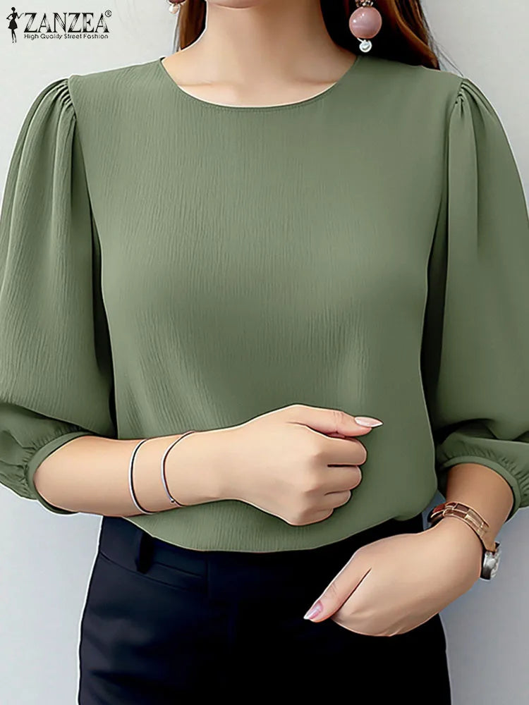 Green blouse with puffed sleeves worn by a model on a plain background