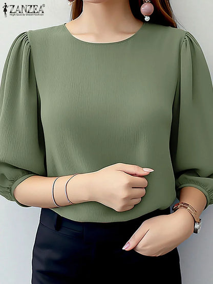 Green blouse with puffed sleeves worn by a model on a plain background
