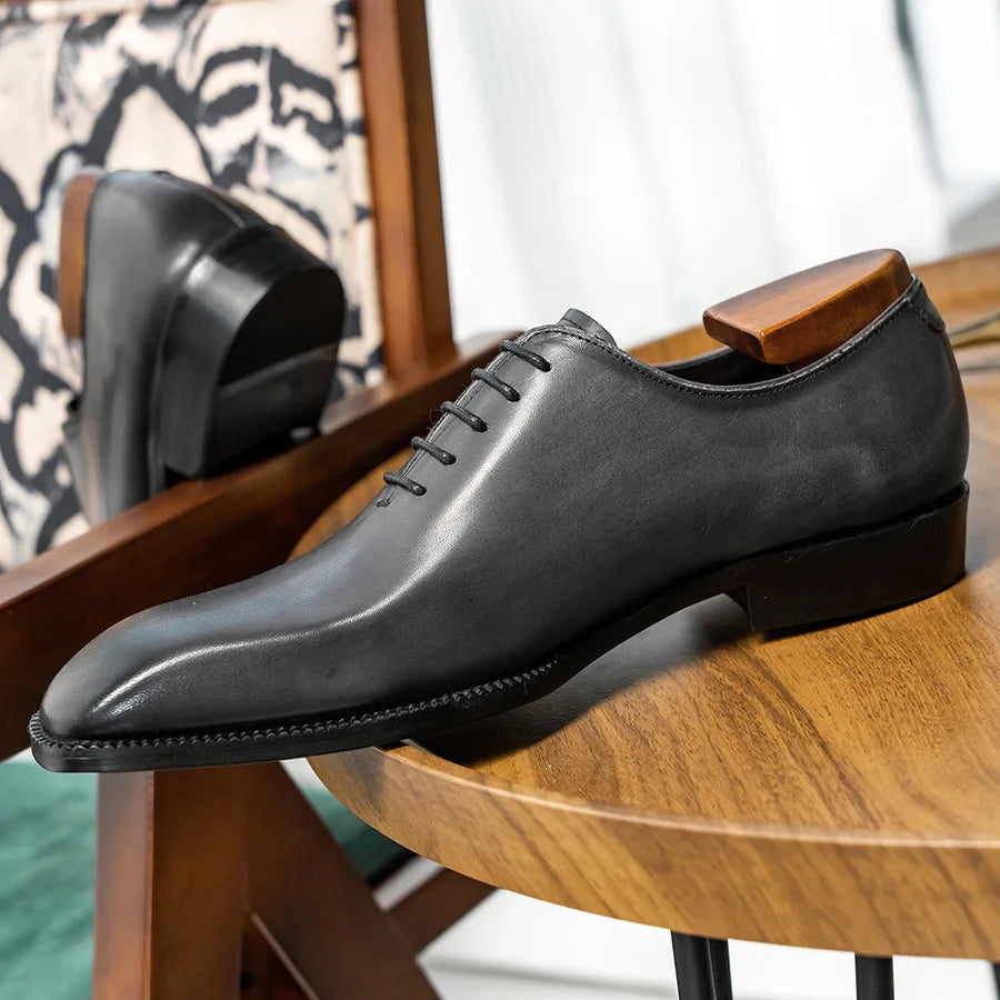 Black leather dress shoe on a wooden chair with a blurred background