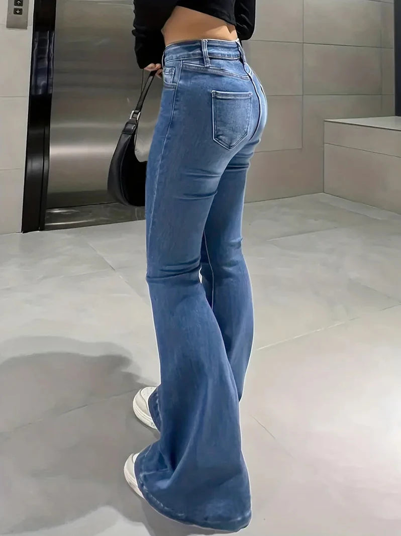 Person wearing blue jeans in a bathroom setting. Women’s slim trumpet jeans mid waist in stretchy soft denim. Casual bell bottoms style with enzyme wash, perfect for UK fashion.