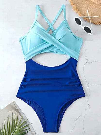 Blue and light blue swimsuit on a white surface with sunglasses and a plant.