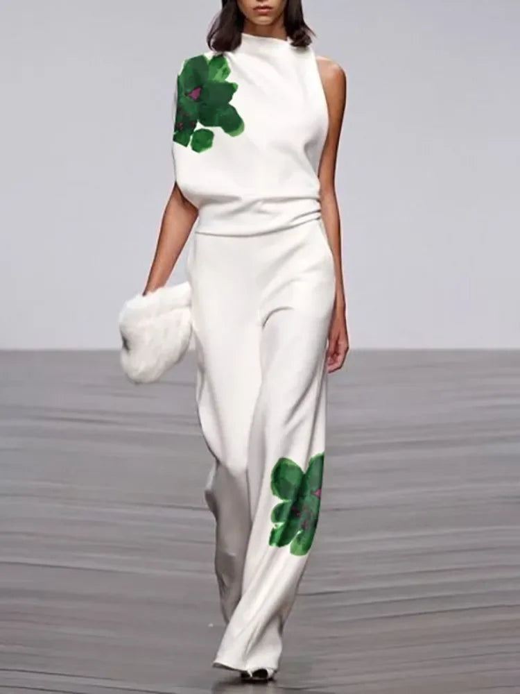 Model wearing a white outfit with green floral patterns on a runway.
