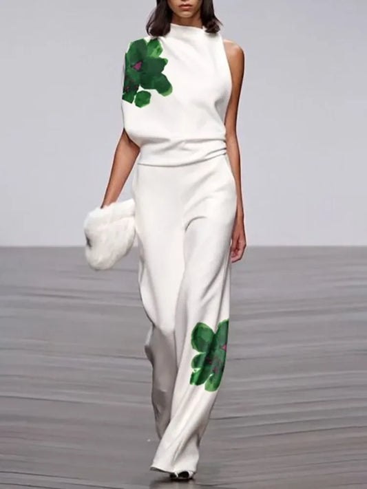 Model wearing a white outfit with green floral patterns on a runway.