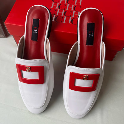 White loafers with red accents on a light gray surface, with a red box in the background.