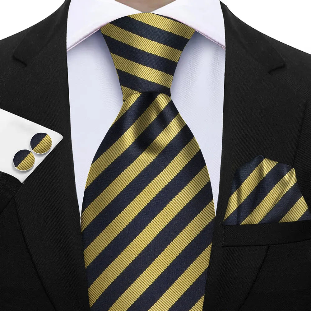 Black and gold striped tie with matching pocket square and cufflinks on a suit. Elegant men’s 3-piece tie set: striped necktie, floral pocket square, matching cufflinks. Fashionable polyester accessories for formal occasions.