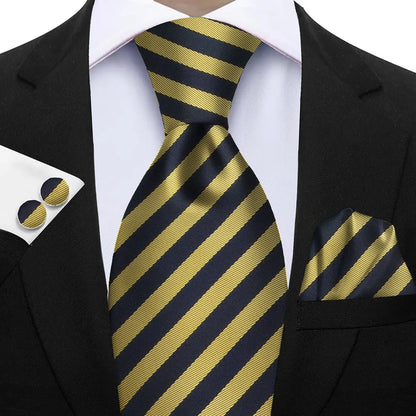 Black and gold striped tie with matching pocket square and cufflinks on a suit. Elegant men’s 3-piece tie set: striped necktie, floral pocket square, matching cufflinks. Fashionable polyester accessories for formal occasions.