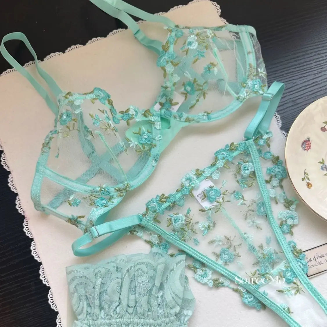Teal floral lingerie set on a lace surface