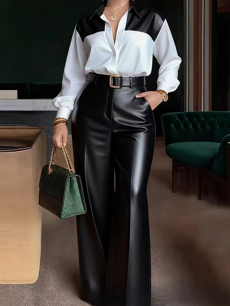 Person wearing a black and white shirt with black leather pants, holding a green handbag in an indoor setting.