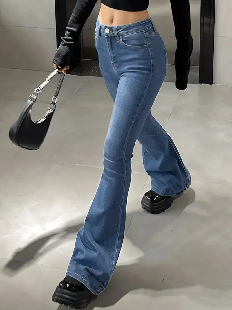 Person wearing blue flared jeans and black shoes, holding a black handbag. Women’s slim trumpet jeans mid waist in stretchy soft denim. Casual bell bottoms style with enzyme wash, perfect for UK fashion.