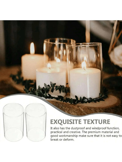 Candle holders with candles on a wooden surface, surrounded by greenery.