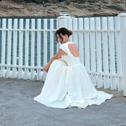 Woman in a white dress sitting on a stone ledge with a scenic background