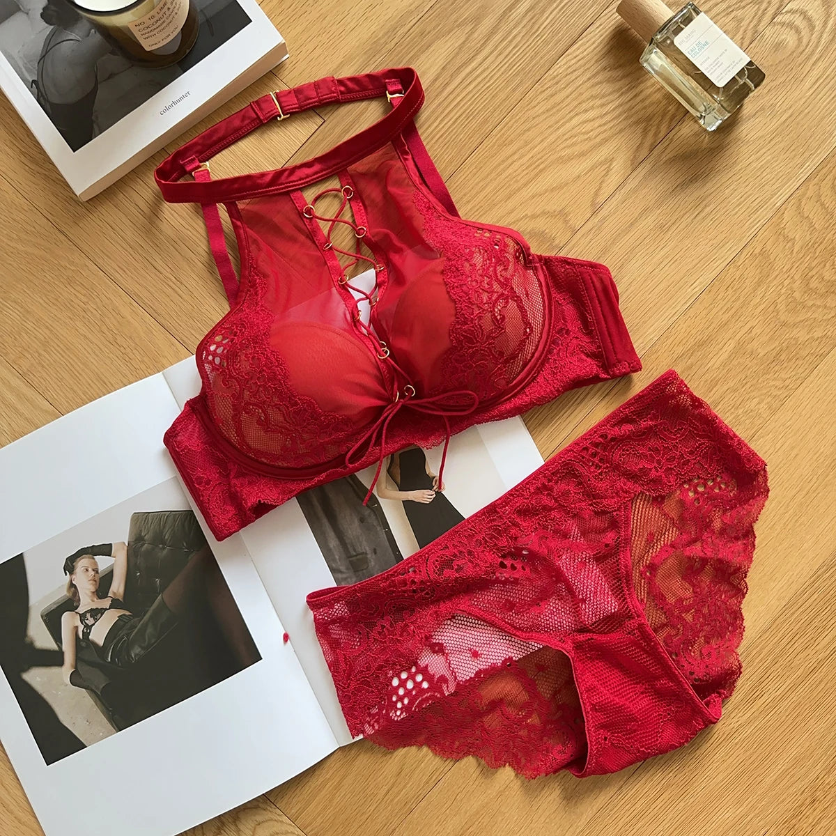 Red lace lingerie set on a wooden surface with photos and a book.