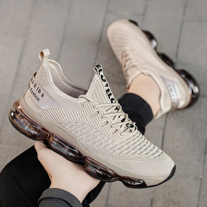 Beige sneakers with air cushion sole held by a person on a gray floor.