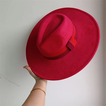 Red hat held by a hand against a plain background