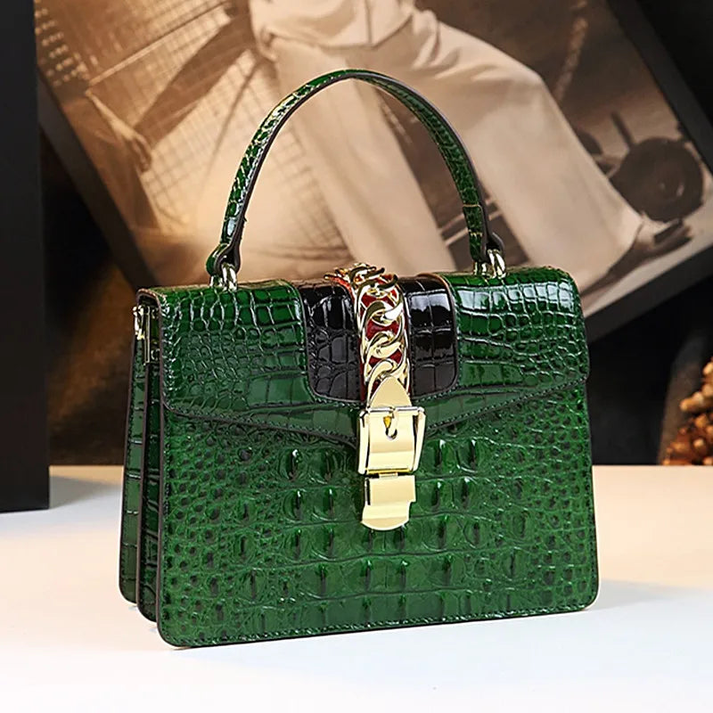 Green crocodile-patterned handbag with a gold lock on a light surface. Small genuine leather crocodile crossbody bag. Hard flap design with soft handle, zipper closure, and interior phone & compartment pockets.