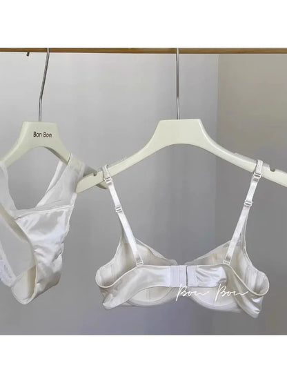 White bra and panties set hanging on a hanger against a neutral background