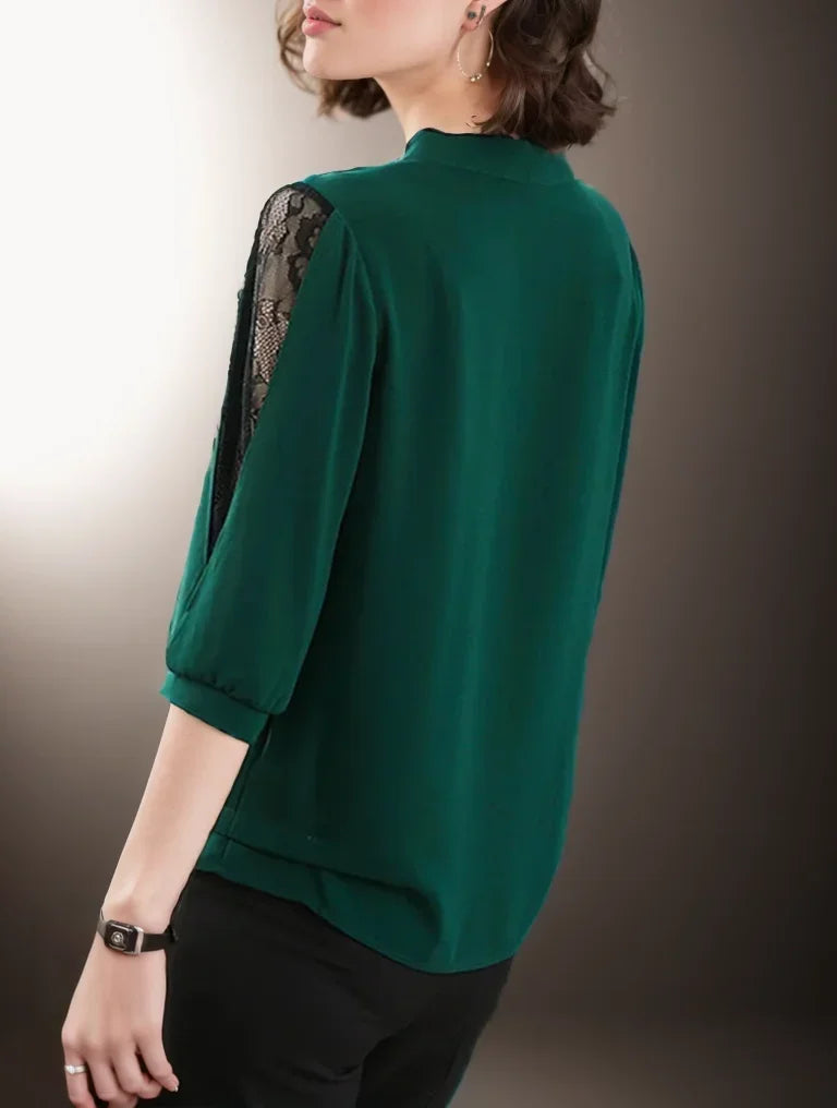 Green blouse with black lace detailing on a plain background
