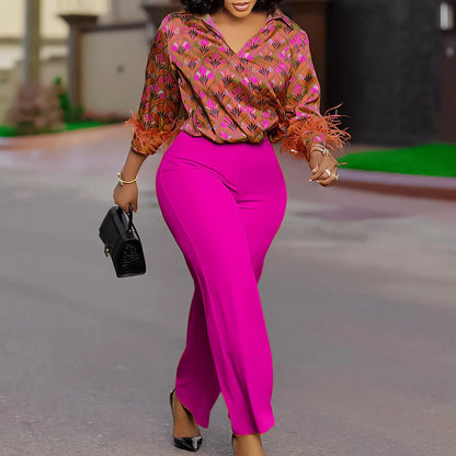 Woman in a colorful top and bright pink pants walking outdoors. African print two-piece polyester outfit with satin printed shirt and high waist wide leg pants. Comfortable, elegant office wear for women.