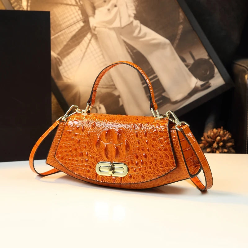 Brown crocodile-patterned handbag on a light surface with a blurred background