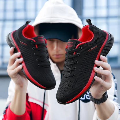 Black and red sneakers held up by a person with a blurred background. Men’s breathable running sneakers with mesh lining, PU insole, EVA outsole, lightweight casual sports shoes, perfect for jogging and walking.