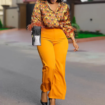 Woman in a patterned top and bright yellow pants walking outdoors. African print two-piece polyester outfit with satin printed shirt and high waist wide leg pants. Comfortable, elegant office wear for women.