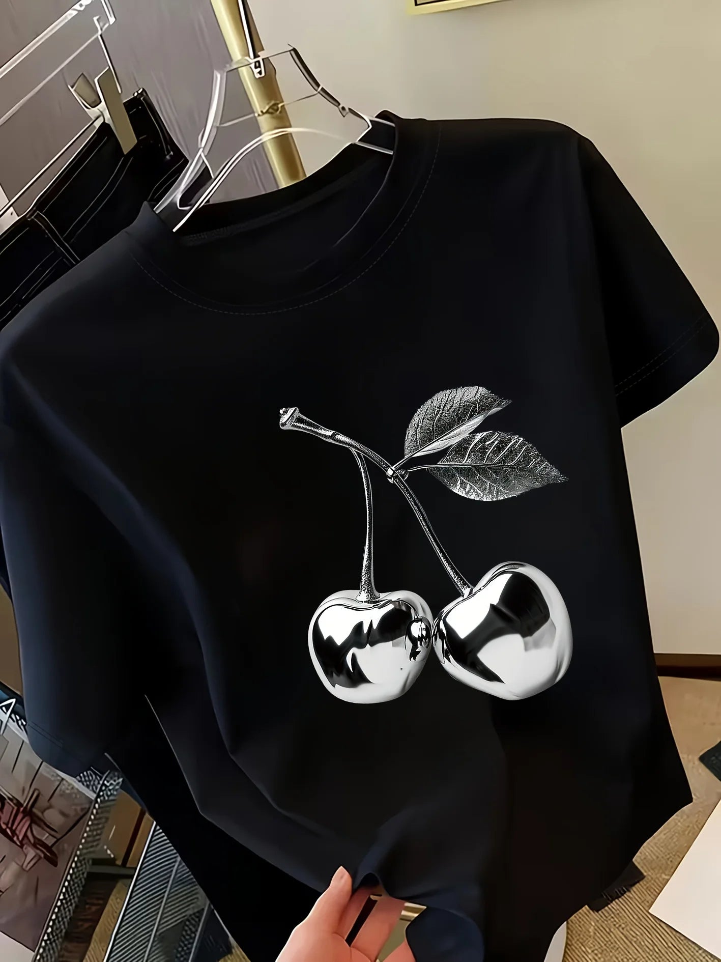 Women's black short sleeve t-shirt with silver metallic cherry print on hanger