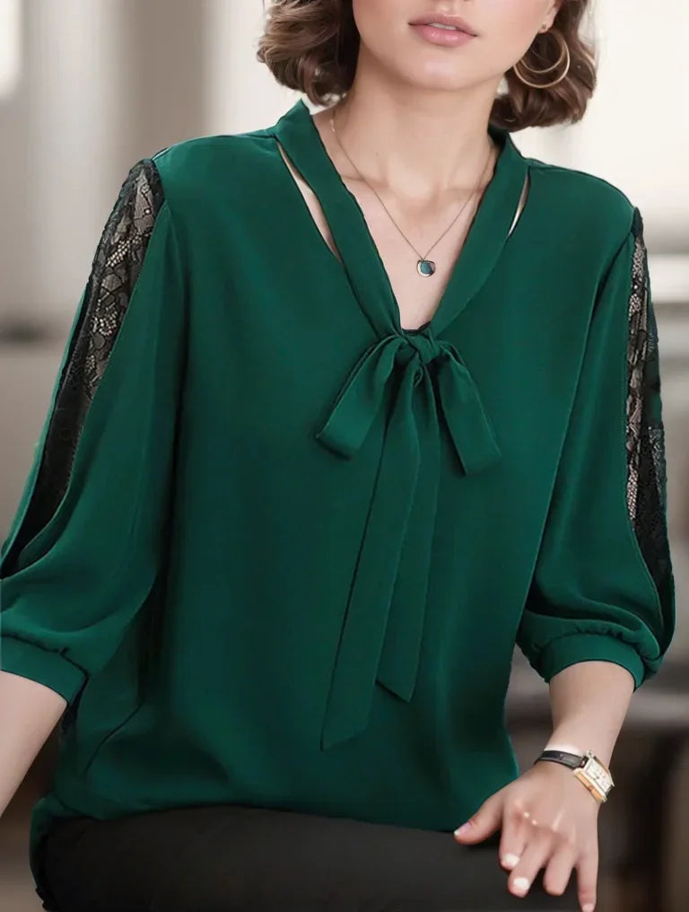 Green blouse with lace sleeves worn by a person, blurred background