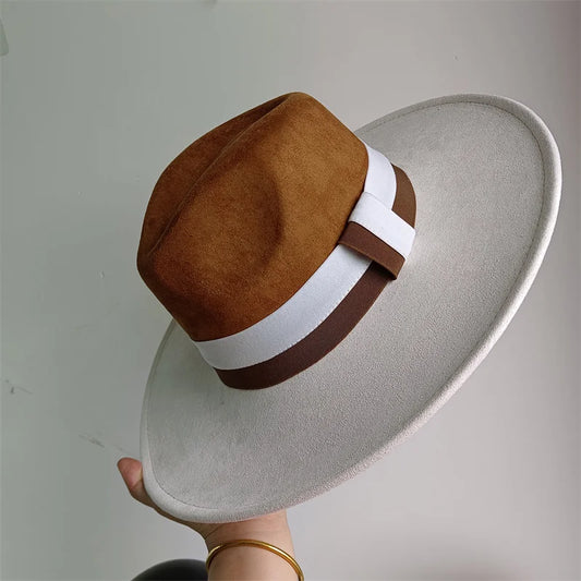 Brown and white hat with a wide brim held against a plain background