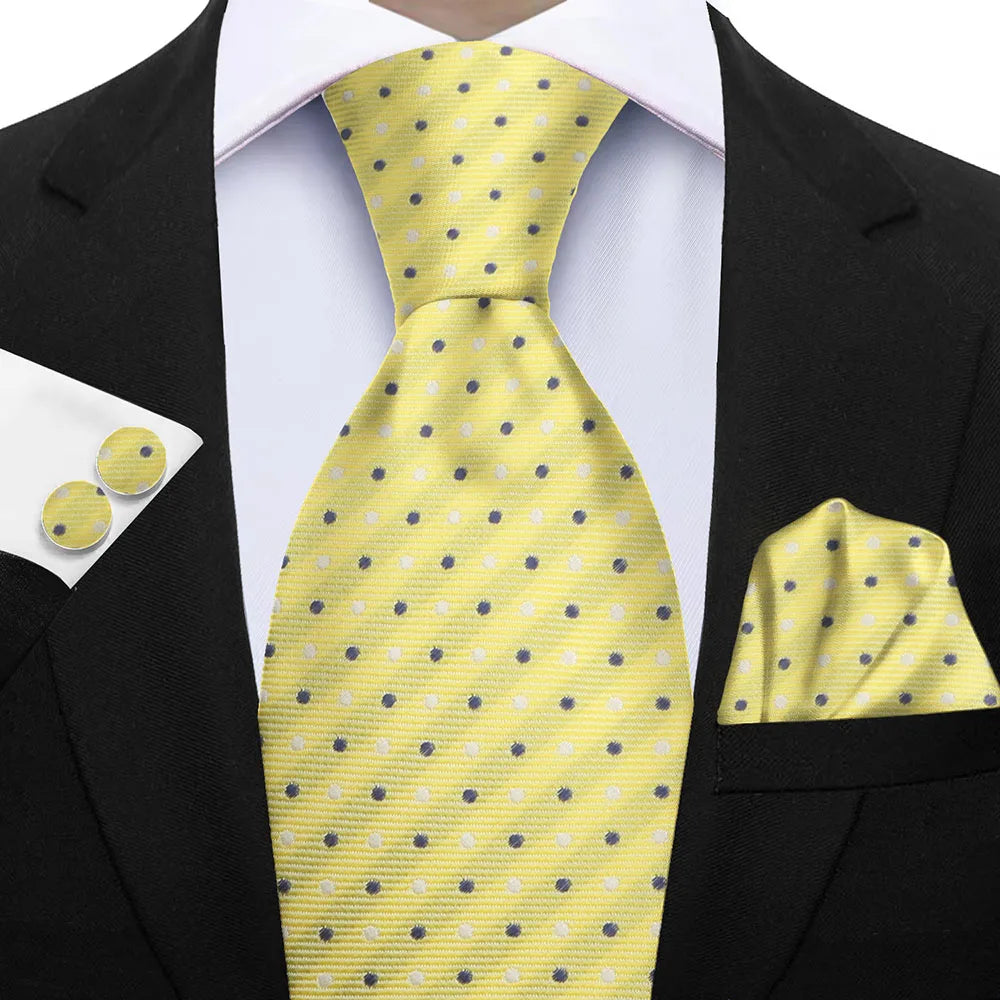 Yellow polka dot tie with matching cufflinks and pocket square on a black suit. Elegant men’s 3-piece tie set: striped necktie, floral pocket square, matching cufflinks. Fashionable polyester accessories for formal occasions.