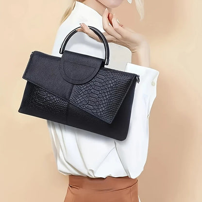Black textured handbag held by a person against a beige background