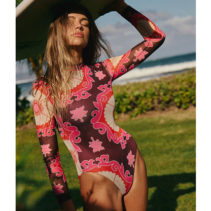 Woman wearing a colorful patterned swimsuit by the ocean.