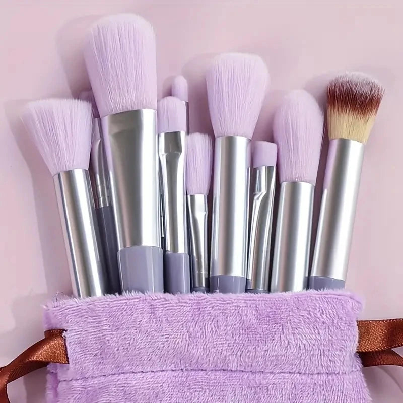 Set of makeup brushes with purple bristles in a purple holder on a pink background. Soft fluffy makeup brush set with wool fiber bristles and plastic handles. Complete set for powder, foundation, eyeshadow, and beauty blending.