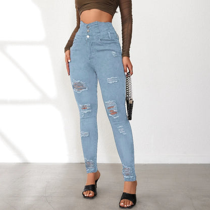 Person wearing distressed light blue jeans on a plain background. Women’s slim pencil jeans, high waist bodycon fit. Casual sheath denim trousers with button detail, ankle length. Trendy Y2K style UK.