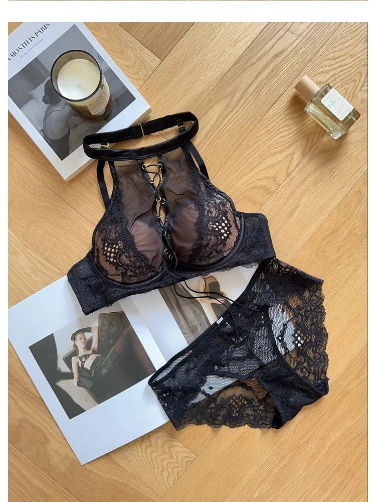 Black lace lingerie set on a wooden surface with a magazine and candle.