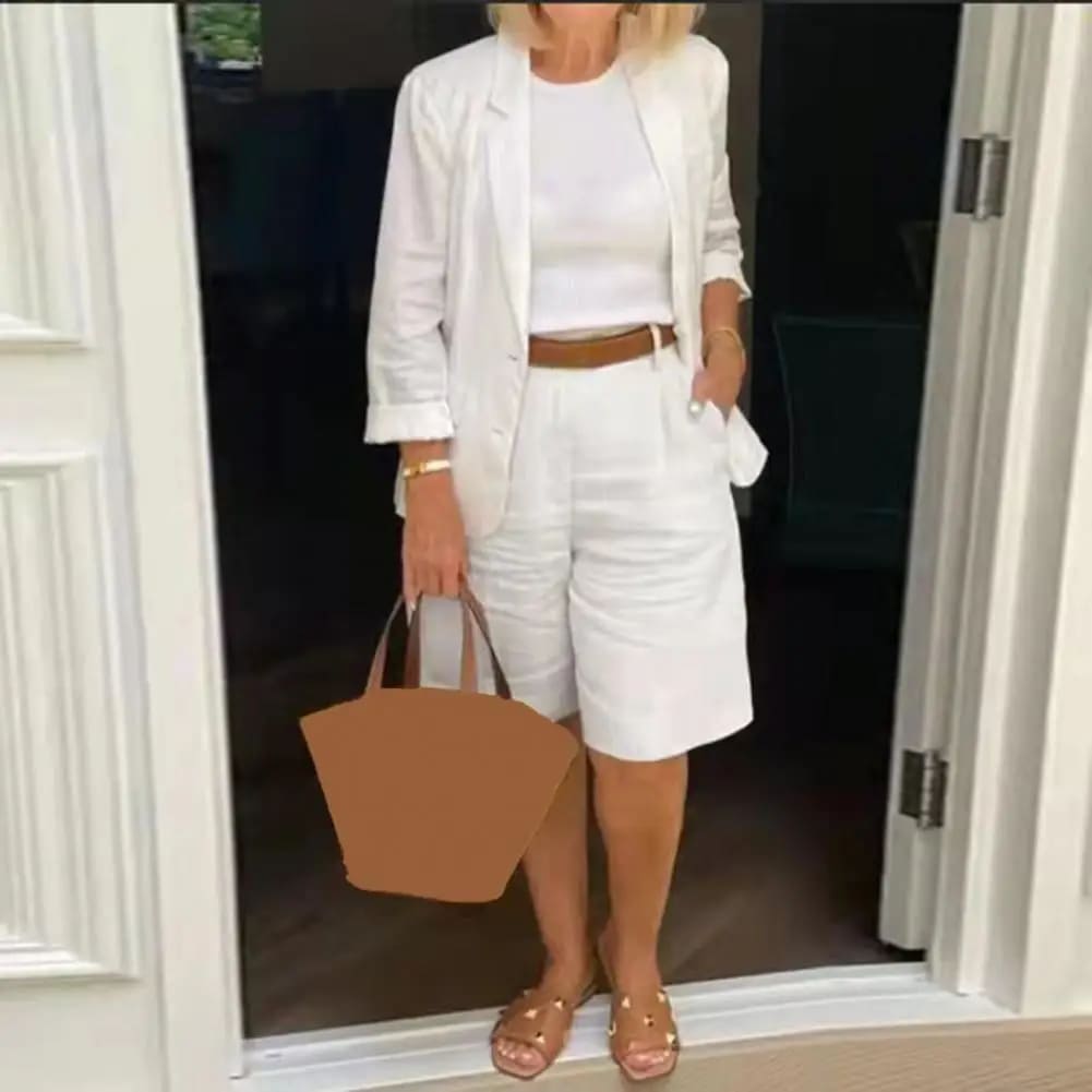 Image of a woman wearing a white Linen Look Blazer and Bermuda Shorts Co-ord Set with a brown belt and straw bag. Ideal smart casual summer outfit.