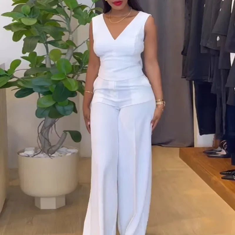 Woman wearing a white outfit standing in a room with a plant and clothing rack. Women’s striped print blouse and elastic waist pants two-piece suit. Sleek, comfortable, breathable office wear perfect for spring and summer.