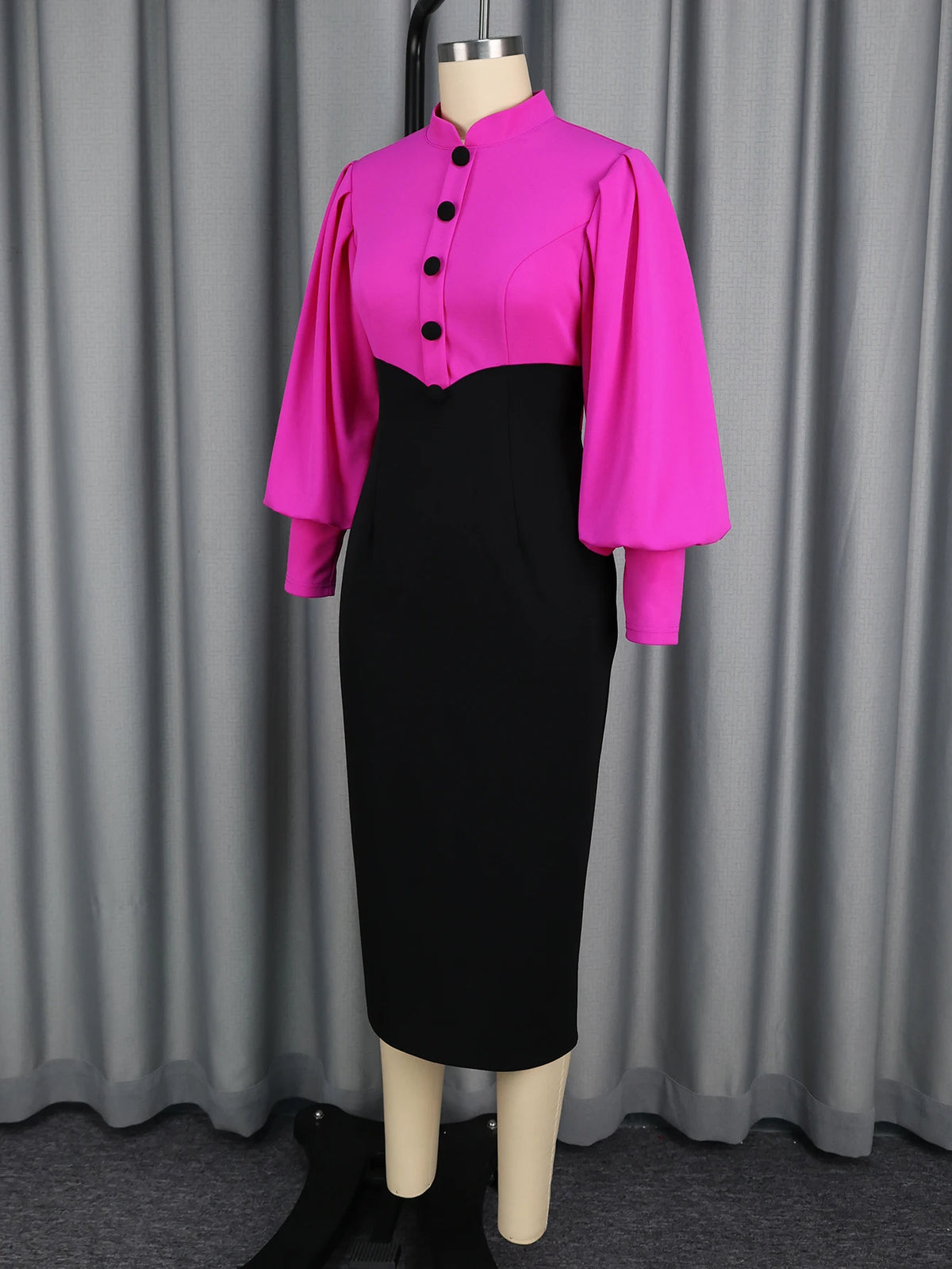 Mannequin wearing a bright pink blouse with black buttons and a black pencil skirt against a gray curtain background.