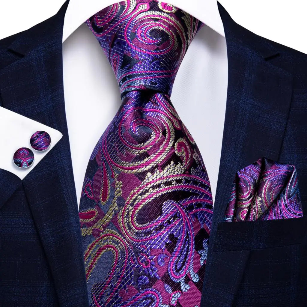 Navy suit with a purple paisley tie, pocket square, and cufflinks on a white background. Men’s luxury paisley silk tie and pocket square set, 8.5cm wide, for business or wedding. Red formal necktie, ftf fashion UK.