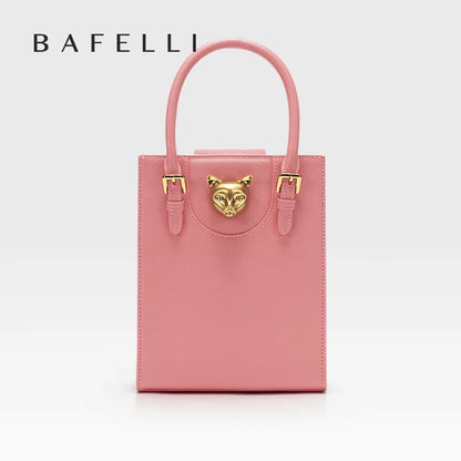 Pink handbag with gold accents on a light gray background, featuring the brand 'Bafelli'. Unisex mini tote crossbody bag in split leather with flap pocket and lock closure. Hard box shape and polyester lining. Casual versatile style.