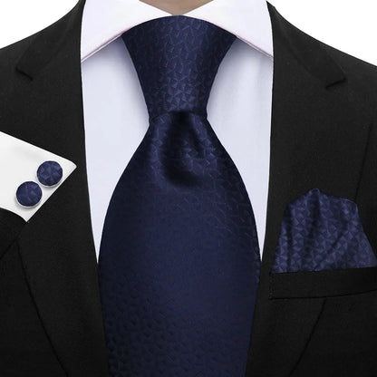 Navy blue tie, pocket square, and cufflinks set on a black suit jacket. Elegant men’s 3-piece tie set: striped necktie, floral pocket square, matching cufflinks. Fashionable polyester accessories for formal occasions.