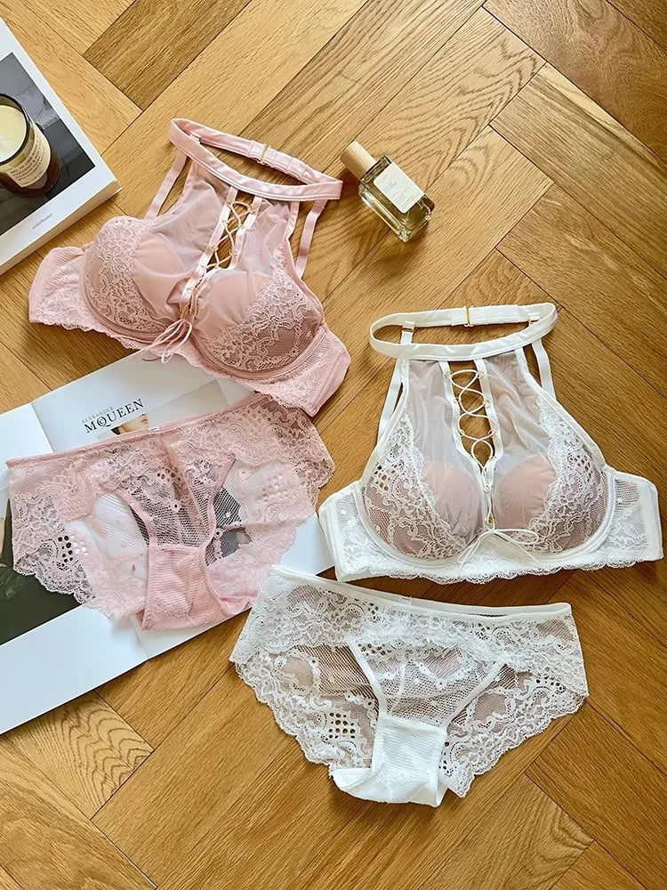 Lace lingerie set including a bra, panties, and garter belt on a wooden floor.