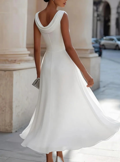 Woman wearing a white dress standing in an urban setting with classical architecture.